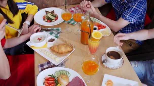 Grupp av vänner som sitter på ett café. Bord fullt av olika mat och dryck — Stockvideo