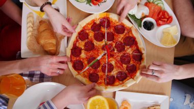 Grup arkadaşıyla kafede oturuyor. Pizza biberli parçalarını alarak