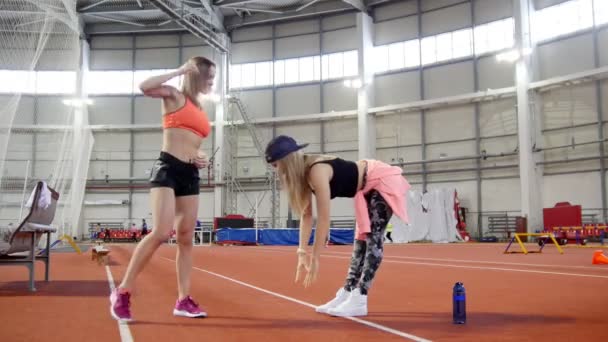 To unge idrettskvinner varmer opp – stockvideo
