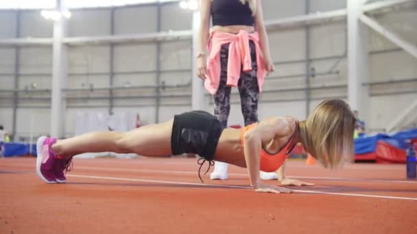 Ung passar atletisk kvinna i sportkläder gör push ups. — Stockvideo