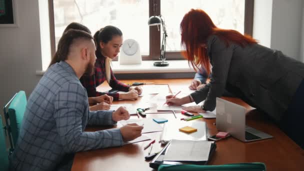 Concept d'entreprise. Une équipe de travail à la conférence. Une femme dessine quelque chose sur le papier et l'équipe applaudit leurs mains 