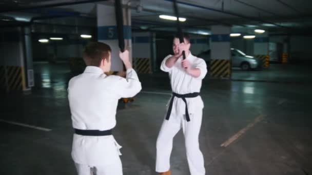 Two young men in kimono training kendo on a parking lot — Stock Video