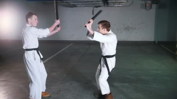 Dois homens em quimono treinando seus kendo em um estacionamento — Vídeo de Stock