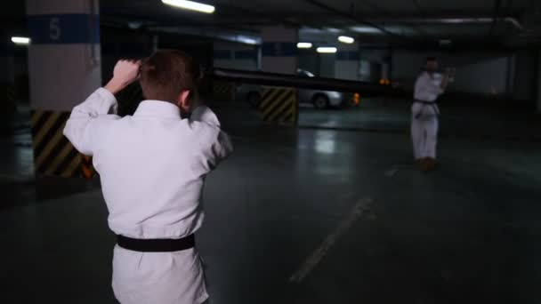 Dois homens em quimono a treinar as suas habilidades de kendo num parque de estacionamento. Luta de espadas — Vídeo de Stock