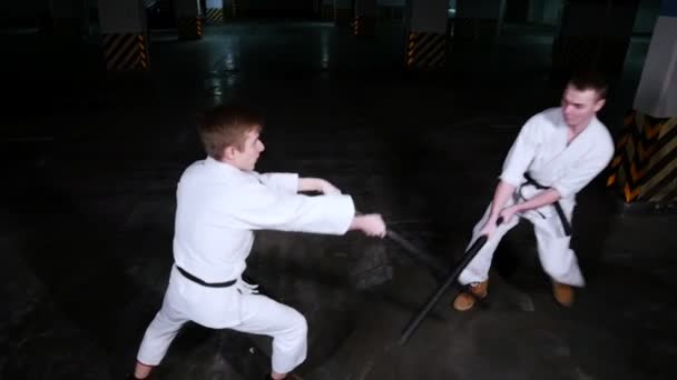 Dos hombres entrenando kendo en un estacionamiento. El hombre defiende un ataque con espada — Vídeo de stock