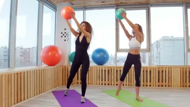 Νεαρές γυναίκες κάνει fitness στο στούντιο κρατώντας μια μπάλα. Ζέσταμα — Αρχείο Βίντεο