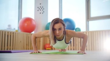 Genç kadın fitness eğitmeni itme yapıyor ups parlak Studio