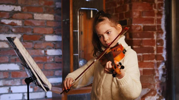Una niña tocando el violín con notas —  Fotos de Stock