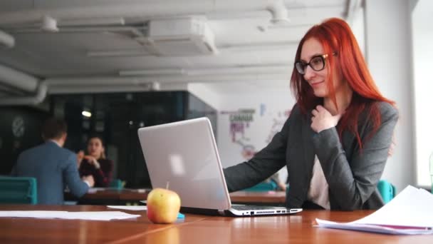 Een gember vrouw zitten op kantoor en werken door de laptop. — Stockvideo