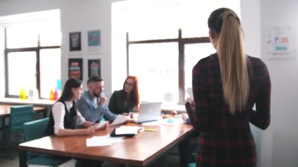 Concept d'entreprise. Une équipe de travail qui organise une conférence. Une femme apporte les documents et l'équipe qui les regarde 