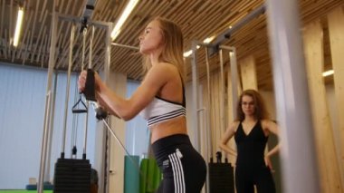 Genç kadın fitness salonunda yapıyor. Güç egzersizleri yapıyor bir kadın. Başka bir kadın onu izlerken