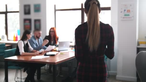 Business concept. A working team having a conference. A woman with a pony tail brings the documents and the team looking at it — Stock Video
