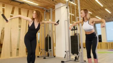 Genç kadının bir antrenör gözetiminde spor salonunda egzersiz yapması ince