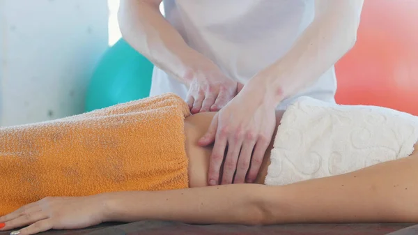 Een jonge vrouw ontvangt een massage. Het masseren van de maag. Zijaanzicht — Stockfoto