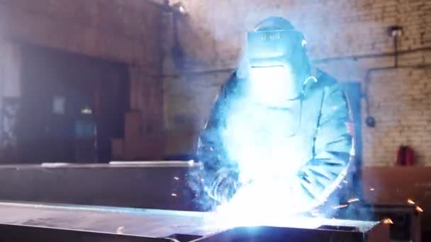 建筑工厂。一个人坐在他的工作场所, 用的是焊接机。明亮的蓝色照明 — 图库视频影像