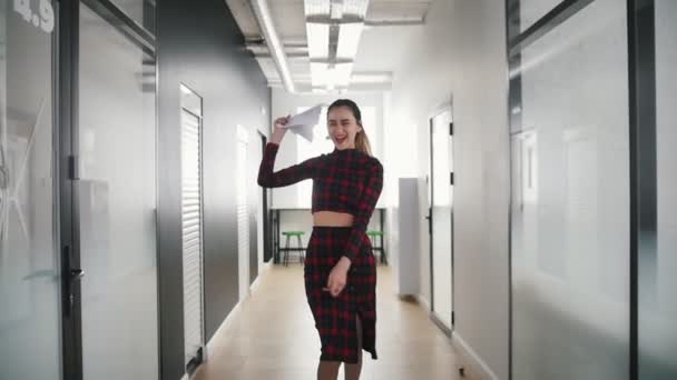 Eine emotionale Geschäftsfrau tanzt im Büroflur und zeigt auf ihre Kollegen und lächelt. — Stockvideo