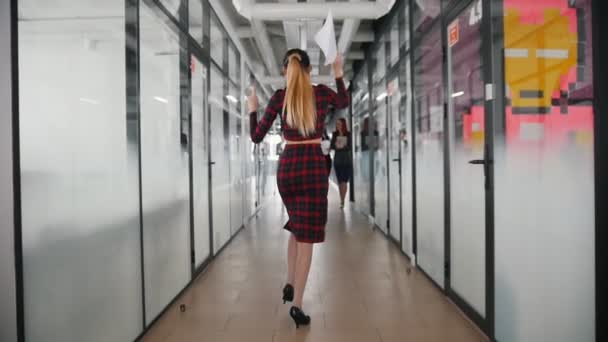 Эмоционально активная деловая женщина, танцующая в офисном коридоре через своих коллег — стоковое видео