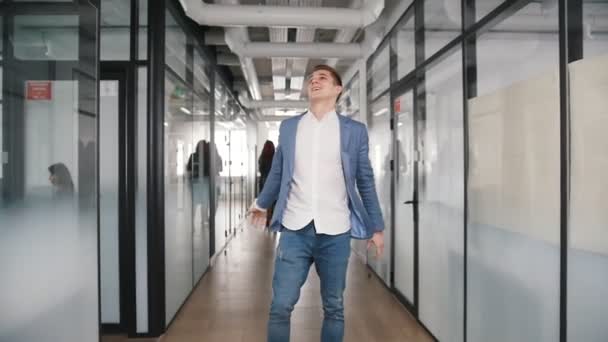 Возбужденный бизнесмен танцует в офисном коридоре и бросает газеты в воздух — стоковое видео