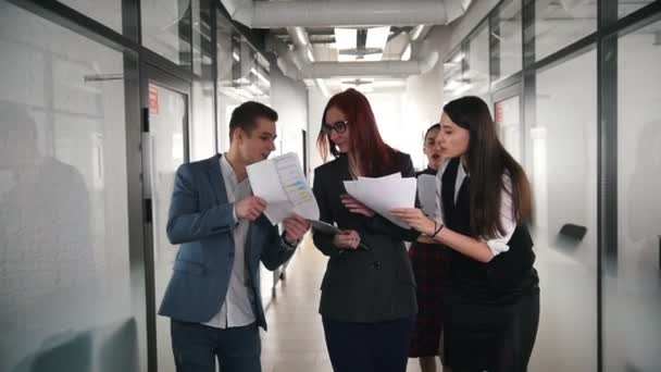 A successful business people walking through the corridor. People showing the documents to their woman chief — Stock Video