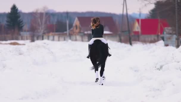 Czas zimowy. Kobieta na koniu w wiosce — Wideo stockowe
