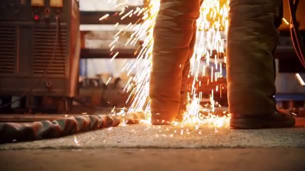 Bygg anläggning. En eld gnistrar faller på golvet nära arbetare fötterna — Stockvideo