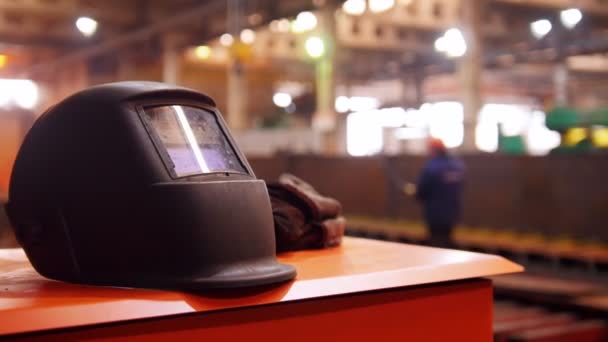 Construcción de plantas. Gente trabajando en el fondo. Un casco negro en primer plano — Vídeo de stock