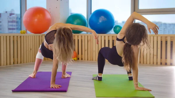 Νεαρές γυναίκες κάνει fitness σχετικά με το χαλάκια γιόγκα στο studio. — Φωτογραφία Αρχείου