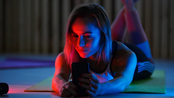 ネオン照明、selfie を取って床に敷設のスポーツ服の若い女性 — ストック写真