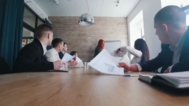 En företagskonferens på kontoret. En kvinna ritar diagram i styrelsen och kollegorna kasta papper i luften — Stockvideo