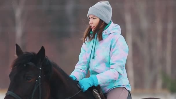 En ung kvinna som rider en häst i vinter skogen — Stockvideo