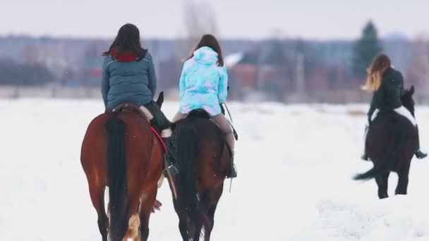 Tre donne a cavallo in un villaggio durante l'inverno con un cane che corre vicino a loro — Video Stock