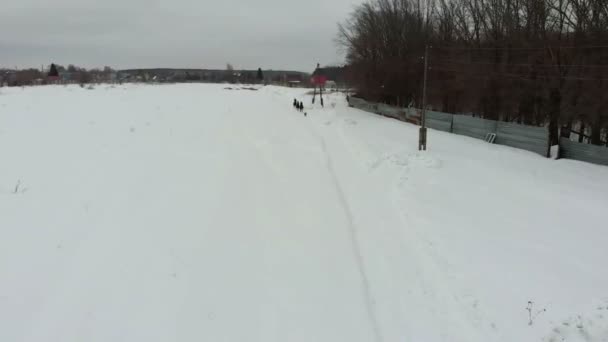 Een groep jonge vrouwen paarden rijden op een besneeuwde veld in een dorp. — Stockvideo