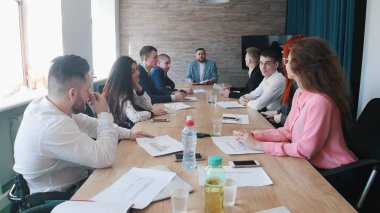 İnsanlar iş toplantısında. Bir şey ve arkadaşları ona bakarak bir şef mavi ceketli açıklar