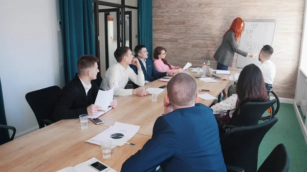 Una conferencia de negocios. Una mujer dibuja los gráficos en el tablero — Foto de Stock