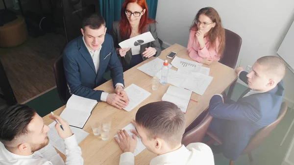 Personas exitosas en la conferencia de negocios hablando junto a la mesa en la oficina brillante — Foto de Stock