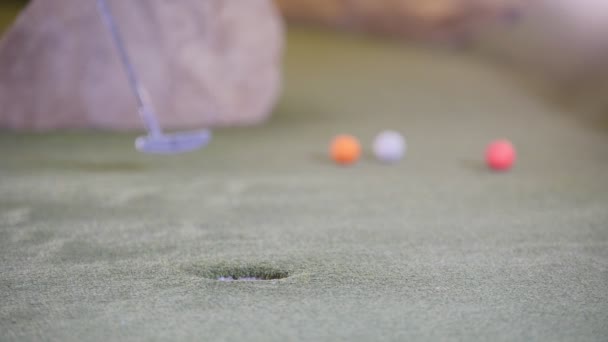 Jugando mini golf. Una persona golpeando varias pelotas de golf en una fila y falla — Vídeos de Stock