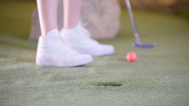 A jogar mini-golfe. Uma pessoa de tênis branco batendo a bola de golfe e perde — Vídeo de Stock