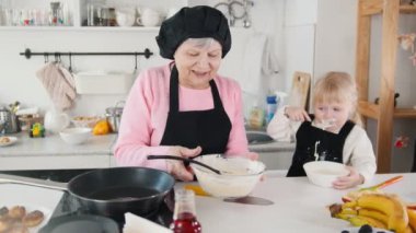 Krep yapmak aile. Hamur üzerinde tava koyarak bir yaşlı kadın