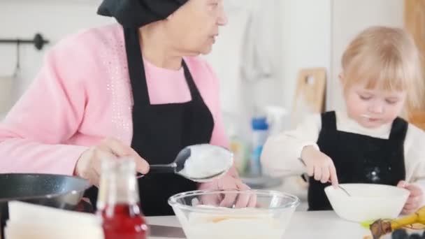 Familie backt Pfannkuchen. eine alte Frau macht einen Teig — Stockvideo