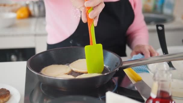 Стара жінка робить млинці на кухні — стокове відео