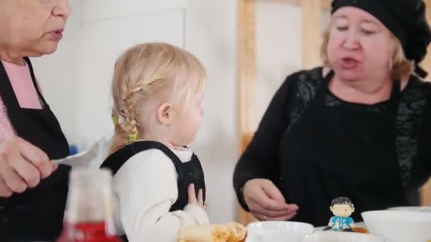 Familie isst Pfannkuchen und trinkt Tee und hält Holzspielzeug in der Hand — Stockvideo