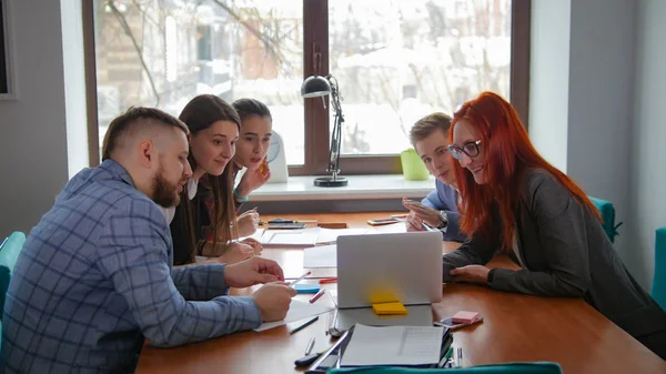 İş kavramı. Onu laptop ve çalışma arkadaşları ekrana bakarak bilgi gösteren kadın