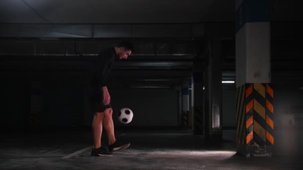 Underjordisk parkeringsplats. Atletisk fotboll man utbildning hans färdigheter i fotboll. Sparka bollen från väggen — Stockvideo