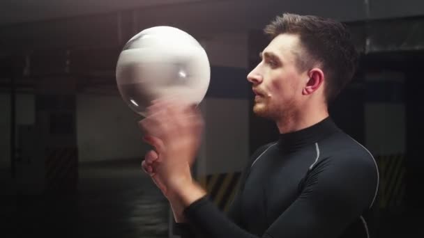 Mélygarázs. Egy fiatal futball férfi forog a labda az ujján — Stock videók