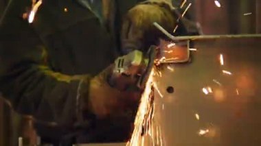 Endüstriyel inşaat fabrikası. Taşlama makinesini kullanan bir adam. Detay yan taşlama. Yangın pırıldları