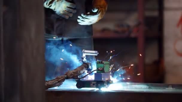 Fábrica de construção. Um homem de capacete usando uma máquina de solda — Vídeo de Stock