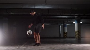 Yeraltı otoparkı. Topu ile temel hileler gösteren genç bir futbol adamı