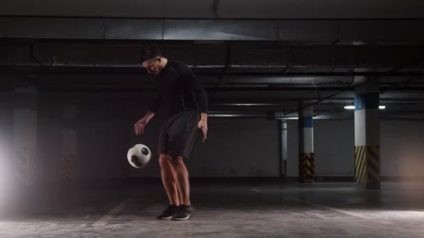 Ondergrondse parkeergarage. Een jonge voetbal man toont de basis trucs met de bal — Stockvideo