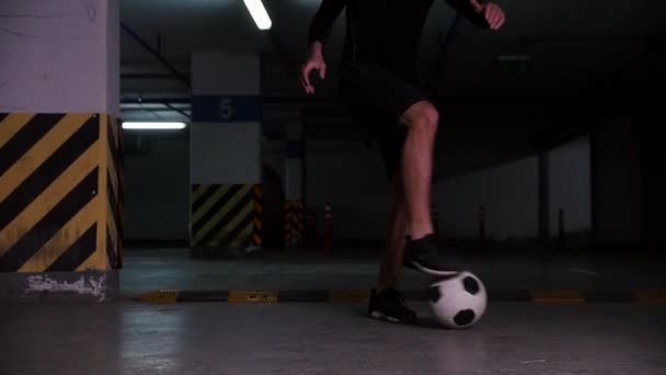 Un footballeur menant le ballon avec des feintes. Formation sur le parking souterrain . — Video