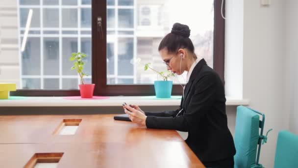 Business concept. A woman in headphones playing game on her phone — Stock Video